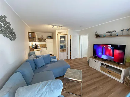 Wohn-/ Essbereich mit gemütlicher Couch (Aufbettung 3. Person, Liegefläche 1,60 m x 2,00 m), Couchtisch, Leselampe, Lowboard mit Smart-TV und einem DAB Radio mit USB-Anschluss und Bluetooth Anschluss 