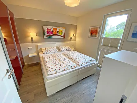 Schlafzimmer mit Boxspringbett (1,80 m x 2,00 m, durchgehender Topper in Komforthöhe), Nachttischablagen mit Wandleuchten,großzügiger Kleiderschrank, Kommode sowie ein Herrendiener