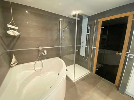 großes Badezimmer mit Fenster, Waschtisch,Wandspiegel, ebenerdiger Regendusche,Wellnesswanne, WC,Haartrockner,Handtuchtrockner,Kosmetikspiegel sowie wohnungseigene Sauna mit Bio-Ofen und LED-Farblicht