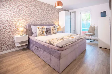 Großes Schlafzimmer mit Boxspringbett, TV und eigenem Badezimmer