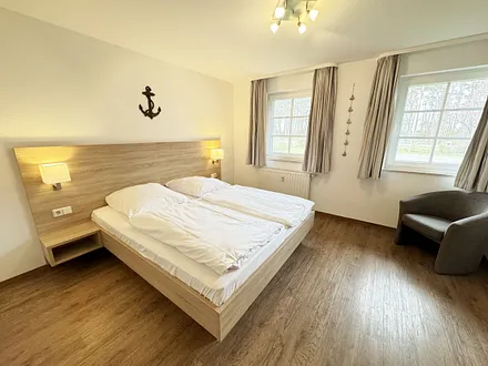 Schlafzimmer hell und modern eingerichtet mit Doppelbett, Komfortmatratzen (2x 0,90 m x 2,00 m), Nachttischkonsolen, Kleiderschrank und Verdunklungsgardinen