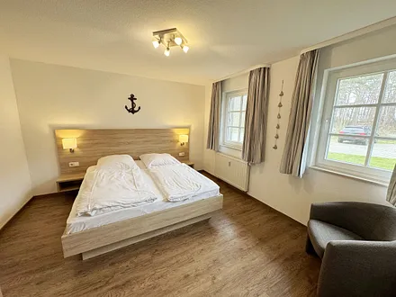 Schlafzimmer hell und modern eingerichtet mit Doppelbett, Komfortmatratzen (2x 0,90 m x 2,00 m), Nachttischkonsolen, Kleiderschrank und Verdunklungsgardinen