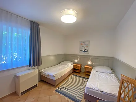 Schlafzimmer mit 2 Einzelbetten (0,90 m x 2,00 m) - auch als Doppelbett stellbar, Nachttischablagen und Kleiderschrank