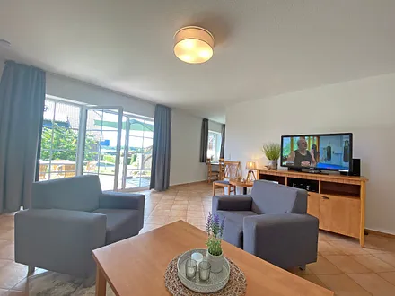 Wohnbereich mit Massivmöbeln, Stehlampe, zwei Sessel und zwei Schlafcouchen (Aufbettung für 5./6. Person - 1,90 m x 2,00 m), 42 Zoll LCD-TV, CD und DVD-Player sowie Gesellschaftsspiele