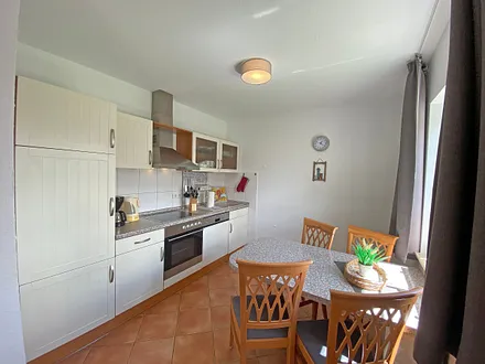 angrenzende Küchenzeile mit Geschirrspüler, Mikrowelle, Ceranfeld, Backofen, Kühlschrank mit Gefrierfach, Wasserkocher, Toaster, Kaffeemaschine und diversen Küchenutensilien 