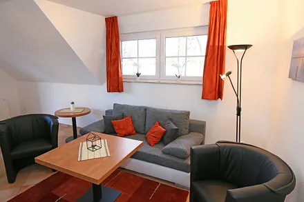 Wohnzimmer mit Schlafcouch (Aufbettung für 5./6. Person 1,37 m x 1,97 m), Stehlampe, zwei Sessel, Smart-TV sowie ein CD und Blu-Ray-Player