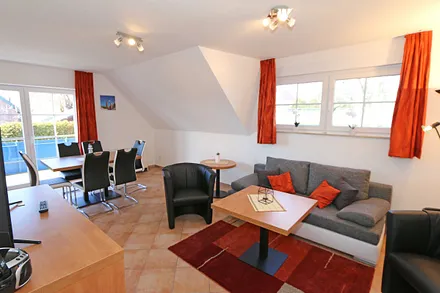 Wohnzimmer mit Schlafcouch (Aufbettung für 5./6. Person 1,37 m x 1,97 m), Stehlampe, zwei Sessel, Smart-TV sowie ein CD und Blu-Ray-Player