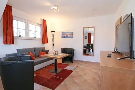 Wohnzimmer mit Schlafcouch (Aufbettung für 5./6. Person 1,37 m x 1,97 m), Stehlampe, zwei Sessel, Smart-TV sowie ein CD und Blu-Ray-Player