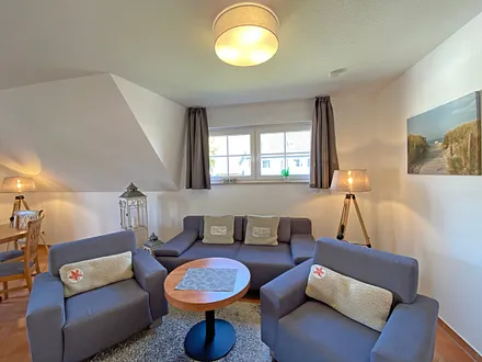 Wohnbereich mit Massivmöbeln, Stehlampe, zwei Sessel, Couch, LCD-TV und ein CD/ DVD-Player