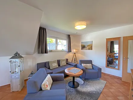 Wohnbereich mit Massivmöbeln, Stehlampe, zwei Sessel, Couch, LCD-TV und ein CD/ DVD-Player