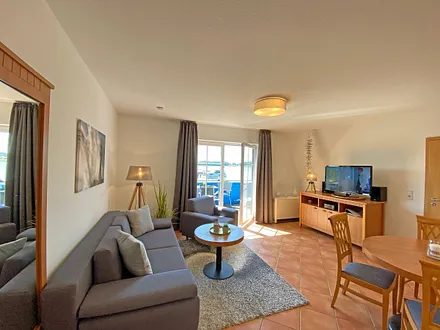 Wohnbereich mit Massivmöbeln, Stehlampe, zwei Sessel und einer Schlafcouch (Aufbettung für 3./4. Person, 1,90 m x 2,00 m), 42 Zoll LCD-TV, CD/ DVD-Player und Gesellschaftsspiele 