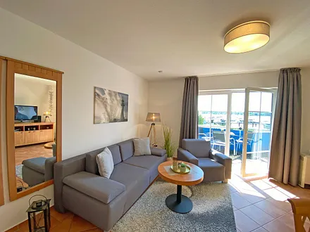 Wohnbereich mit Massivmöbeln, Stehlampe, zwei Sessel und einer Schlafcouch (Aufbettung für 3./4. Person, 1,90 m x 2,00 m), 42 Zoll LCD-TV, CD/ DVD-Player und Gesellschaftsspiele 