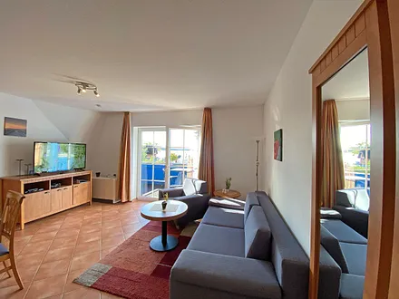 Wohnbereich mit Massivmöbeln, Stehlampe, Sessel und einer Schlafcouch (Aufbettung für 3./4. Person, 1,90 m x 1,40 m), Gesellschaftsspielen, 42 Zoll Smart-TV & Mini-Stereo-Anlage mit DAB Radio