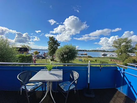 bestuhlter, großzügiger Balkon mit Sonnenschirm und Panoramablick auf den Selliner See