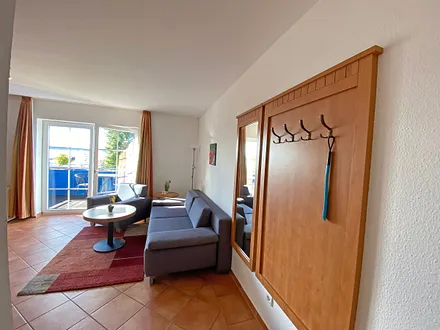 Wohnbereich mit Massivmöbeln, Stehlampe, Sessel und einer Schlafcouch (Aufbettung für 3./4. Person, 1,90 m x 1,40 m), Gesellschaftsspielen, 42 Zoll Smart-TV & Mini-Stereo-Anlage mit DAB Radio