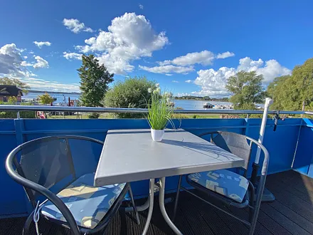 bestuhlter, großzügiger Balkon mit Sonnenschirm und Panoramablick auf den Selliner See