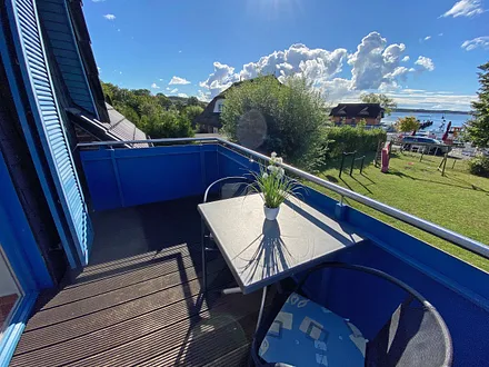 bestuhlter, großzügiger Balkon mit Sonnenschirm und Panoramablick auf den Selliner See