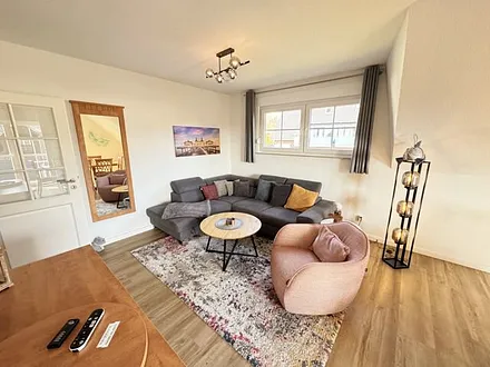 Wohnbereich mit Couch, Sessel, Couchtisch, Sideboard, Smart-TV, CD-Player und ein Radio