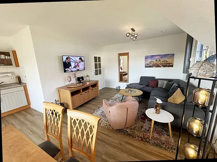 Wohnbereich mit Couch, Sessel, Couchtisch, Sideboard, Smart-TV, CD-Player und ein Radio 