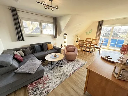 Wohnbereich mit Couch, Sessel, Couchtisch, Sideboard, Smart-TV, CD-Player und ein Radio 