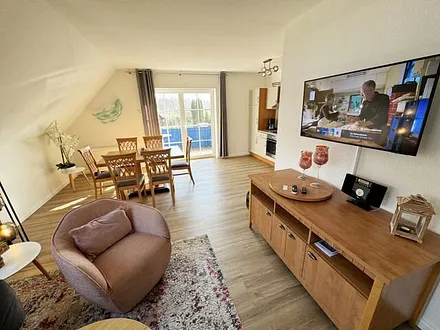 Wohnbereich mit Couch, Sessel, Couchtisch, Sideboard, Smart-TV, CD-Player und ein Radio