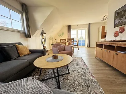 Wohnbereich mit Couch, Sessel, Couchtisch, Sideboard, Smart-TV, CD-Player und ein Radio