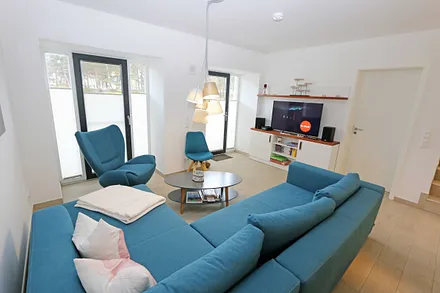 Wohnzimmer mit komfortabler Eckcouch, Couchtisch, Sideboard, Smart-TV sowie eine Mini-Stereo-Anlage mit Bluetooth und USB-Anschluss