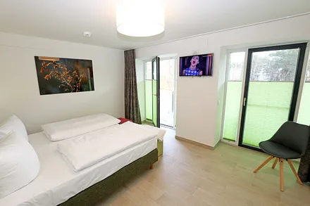 Schlafzimmer mit einem Doppelbett (1x 1,60 m x 2,00 m, 1x 0,90 m x 2,00 m ausziehbar auf 1,80 m und 1x 1,80 m x 2,00 m), Nachttischablagen mit Beleuchtung und USB Anschlüssen sowie Kleiderschränken