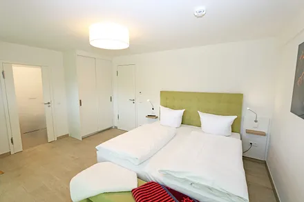 Schlafzimmer mit einem Doppelbett (1x 1,60 m x 2,00 m, 1x 0,90 m x 2,00 m ausziehbar auf 1,80 m und 1x 1,80 m x 2,00 m), Nachttischablagen mit Beleuchtung und USB Anschlüssen sowie Kleiderschränken