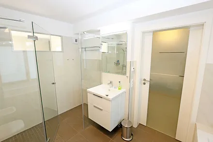 Bäder mit jeweils einem WC, ebenerdiger Dusche, Kosmetikspiegel, Fön, Handtuchtrockner sowie einem Waschplatz mit großzügigem Spiegel und Ablagefläche