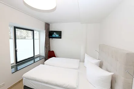 Schlafzimmer mit einem Doppelbett (1x 1,60 m x 2,00 m, 1x 0,90 m x 2,00 m ausziehbar auf 1,80 m und 1x 1,80 m x 2,00 m), Nachttischablagen mit Beleuchtung und USB Anschlüssen sowie Kleiderschränken