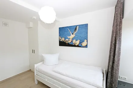 Schlafzimmer mit einem Einzelbett (0,90 m x 2,00 m), Nachttischablage mit Beleuchtung und USB Anschlüssen sowie einem Kleiderschrank