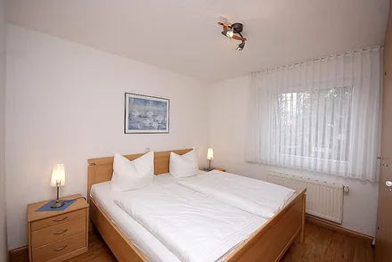 Schlafzimmer mit Doppelbett, Kleiderschrank & Verdunklungsjalousie vor dem Fenster