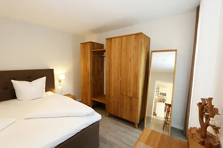 Schlafzimmer ist mit einem Boxspringbett (1,80 m x 2,00 m), durchgehenden Topper, Nachttischablagen, Kosmetiktisch, Kleiderablage sowie einen Kleiderschrank