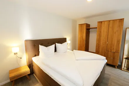 Schlafzimmer ist mit einem Boxspringbett (1,80 m x 2,00 m), durchgehenden Topper, Nachttischablagen, Kosmetiktisch, Kleiderablage sowie einen Kleiderschrank