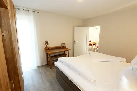 Schlafzimmer ist mit einem Boxspringbett (1,80 m x 2,00 m), durchgehenden Topper, Nachttischablagen, Kosmetiktisch, Kleiderablage sowie einen Kleiderschrank