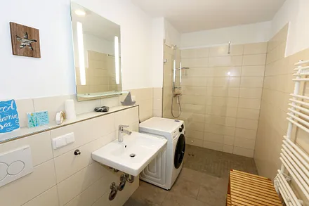 innenliegendes Badezimmer mit ebenerdiger Regendusche, Waschtisch, WC, Kosmetikspiegel, Waschmaschine, Fön und beheizbaren Handtuchtrockner