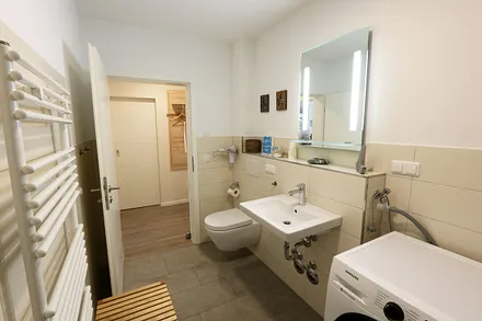 innenliegendes Badezimmer mit ebenerdiger Regendusche, Waschtisch, WC, Kosmetikspiegel, Waschmaschine, Fön und beheizbaren Handtuchtrockner