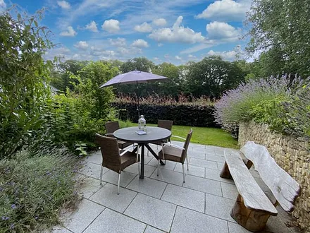 bestuhlte Terrasse (Süd/Ost) mit Sonnenschirm und einem Weber-Holzkohlegrill