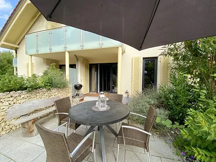 bestuhlte Terrasse (Süd/Ost) mit Sonnenschirm und einem Weber-Holzkohlegrill