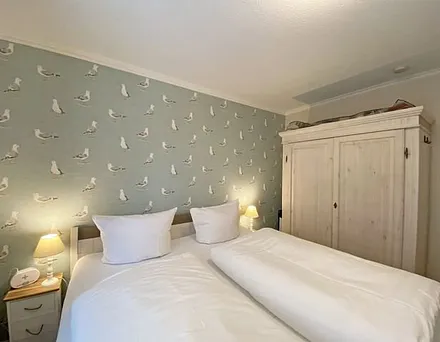 Schlafzimmer mit Doppelbett in Komforthöhe (1,80 m x 2,00 m), verstellbare Lattenroste, Nachtischablagen mit Lampen sowie ein zweitüriger Kleiderschrank