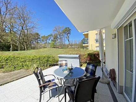 bestuhlte Terrasse mit Sonnenschirm und zwei Sonnenliegen