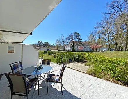 bestuhlte Terrasse mit Sonnenschirm und zwei Sonnenliegen