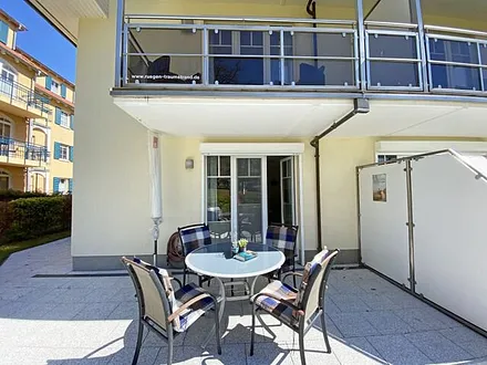 bestuhlte Terrasse mit Sonnenschirm und zwei Sonnenliegen