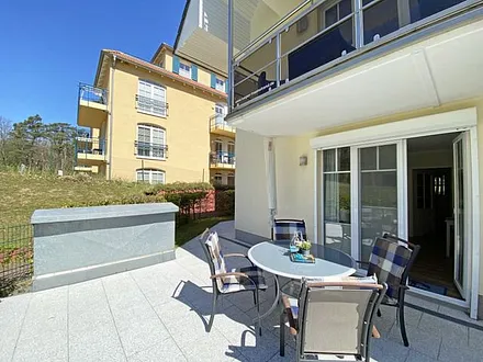 bestuhlte Terrasse mit Sonnenschirm und zwei Sonnenliegen