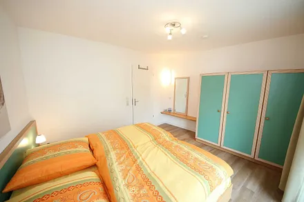 Schlafzimmer mit Doppelbett (1,80 m x 2,00 m), Schrank, Ablageflächen und bodentiefe Fenster mit Verdunklungsvorhängen