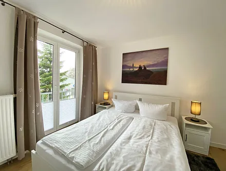 Schlafzimmer mit Doppelbett (1,60 m x 2,00 m, H3), Nachttischablagen, Kleiderschrank, Kommode, Smart-TV sowie Verdunklungsvorhang