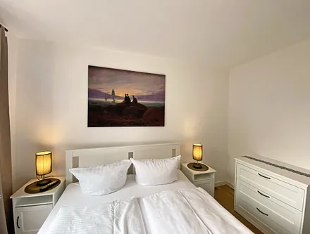 Schlafzimmer mit Doppelbett (1,60 m x 2,00 m, H3), Nachttischablagen, Kleiderschrank, Kommode, Smart-TV sowie Verdunklungsvorhang