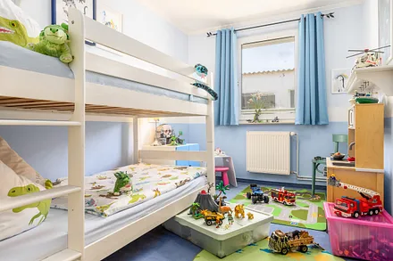 Das Kinderzimmer mit Verdunkelungsgardinen, Spielzeug und Kinderspielküche.