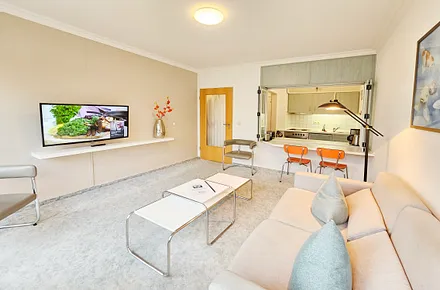 Flat-TV, Couch, Sessel und Blick zur Küche